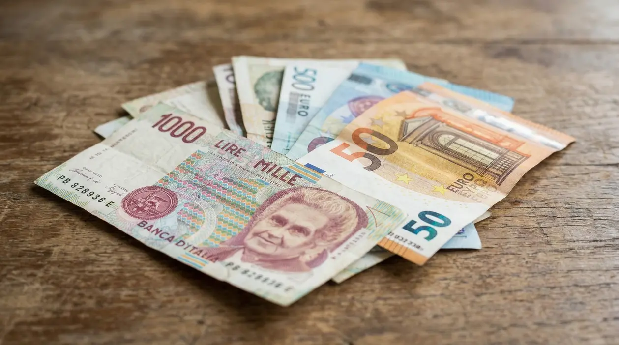 Banconote in lire italiane ed euro disposte su un tavolo in legno