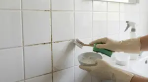 Pulizia delle piastrelle del bagno con spazzola e rimedio fai da te