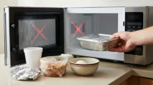 Una mano inserisce un contenitore in alluminio nel microonde accanto ad altri oggetti non adatti