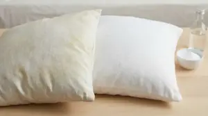 Due cuscini su un tavolo, uno ingiallito e l'altro bianco, con bicarbonato e bottiglia d'acqua