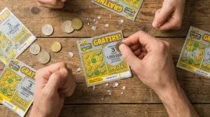 Mani mentre grattano biglietti Gratta e Vinci su un tavolo di legno