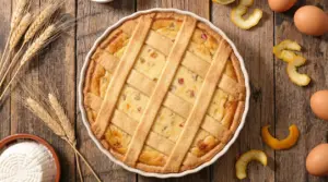 Pastiera napoletana con sette strisce di pasta frolla su tavolo rustico con ingredienti