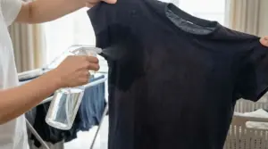 Una persona spruzza un liquido sotto le ascelle di una maglietta scura